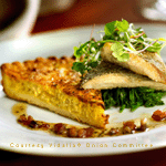 Sweet Vidalia Onion Quiche A gourmet Vidalia Onion dish is presented with great care, featuring a perfectly cooked garnishments resting on a bed of greens, accompanied by a slice of golden-brown Vidalia Onion quiche. The plate is garnished with a light, fresh salad and some sprinkled nuts, adding a range of textures and flavors.